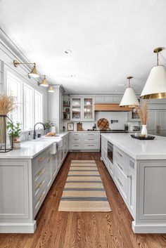 a large kitchen with white cabinets and wood flooring, along with an area rug in the middle