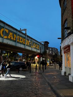 people sitting on the ground in front of a building with a sign that says camden place