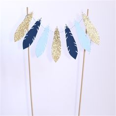 a cake topper that has some feathers on it and is blue, gold and white