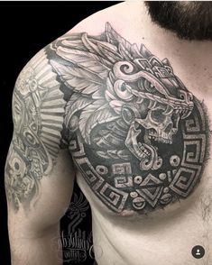 a man's chest with a tattoo on it and a skull in the center