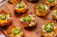 small appetizers with green peppers and cheese are on a wooden platter, ready to be eaten