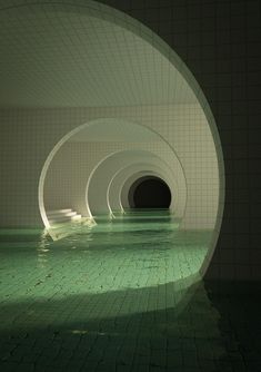 an underground swimming pool with green tiles and water in the center, surrounded by white walls