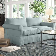 a living room with blue couches and coffee table in front of large glass windows