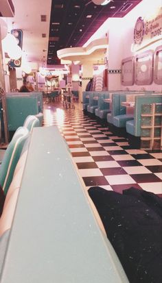 the interior of a diner with checkered flooring and blue booths on either side