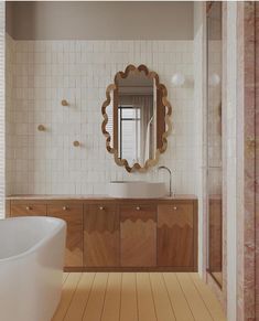 a bathroom with a sink, mirror and bathtub on the floor in front of a tiled wall