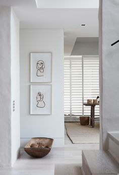 a bowl is sitting on the floor in front of two framed pictures and a stair case