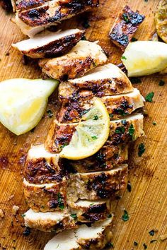 grilled chicken with lemon slices and parsley on a cutting board