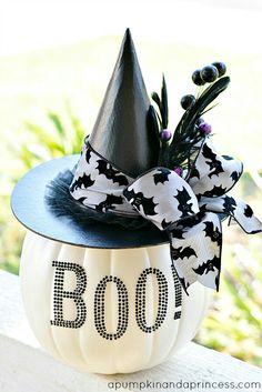 a black and white pumpkin decorated with a bow on it's head that says boo