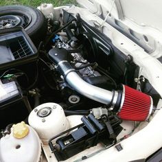 the engine compartment of a white car with its hood up and air intake in it