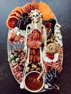 a plate filled with food that includes meats, fruit and vegetables as well as a skeleton