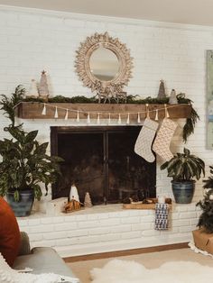 a living room decorated for christmas with potted plants and stockings hanging from the fireplace