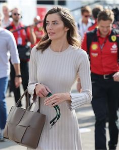 a woman in a white dress carrying a brown purse