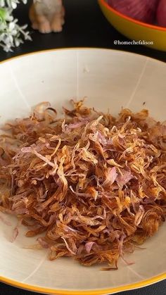 a white bowl filled with shredded onions on top of a table next to a yellow and white plate