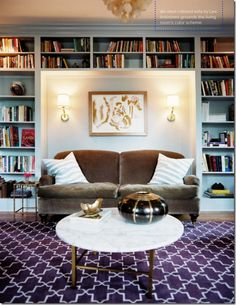 a living room filled with furniture and lots of bookshelves on the wall behind it