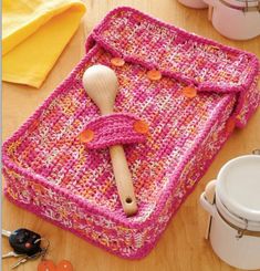 a crocheted dishcloth with a wooden spoon in it on top of a table