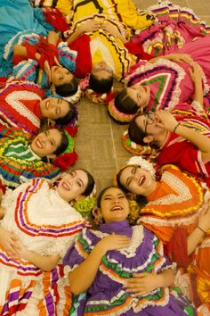 a group of women laying on the ground in colorful dresses and headdresss