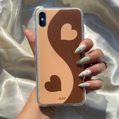 a woman's hand holding an iphone case with white and brown designs on it