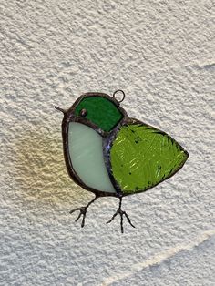 a stained glass bird sitting on top of a white wall