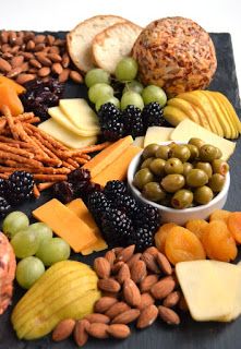 an assortment of cheeses, fruits and nuts arranged on a slate platter for a snack