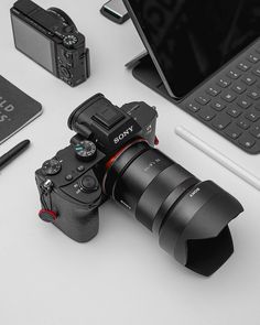 a sony camera sitting on top of a white table next to a laptop and other electronics