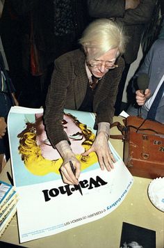 an older woman is signing a poster at a party