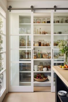 an open pantry with glass doors and shelves filled with fruit, vegetables, and other items