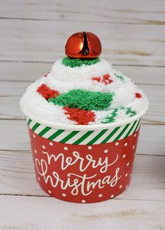 a cupcake decorated with green, red and white frosting is sitting on a table