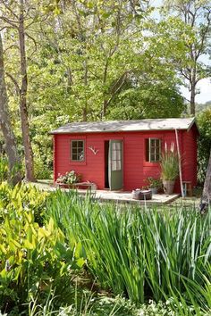 a small red house surrounded by trees and plants