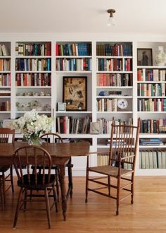 a dining room table and chairs with bookshelves in the background