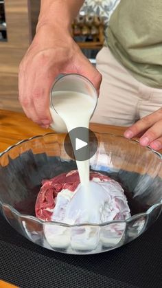 a person pouring milk into a bowl filled with meat