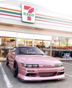 a pink car parked in front of a store