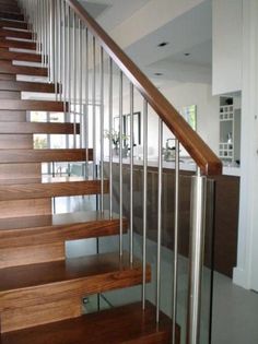 a wooden stair case with metal handrails and glass balconies in a house