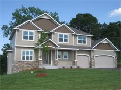 a two story house in the middle of a grassy area