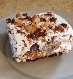 a piece of cake sitting on top of a plate covered in frosting and nuts