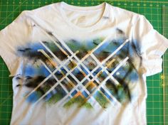 a white t - shirt with an abstract design on the front and back, sitting on a green cutting board