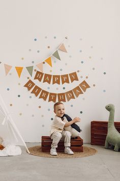 a young boy sitting on a stool in front of a birthday banner and teepee