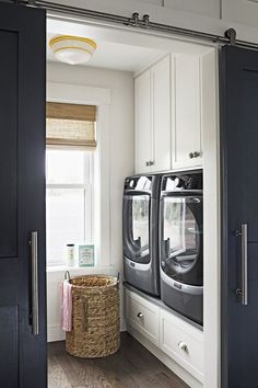 a washer and dryer in a room with white walls, wood floors and black doors