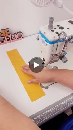 a woman is using a sewing machine to sew something on a piece of paper