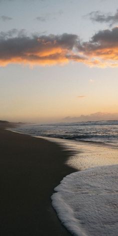 the sun is setting at the beach with waves coming in