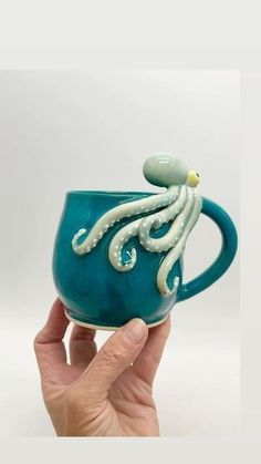 a hand holding a ceramic cup with an octopus on it