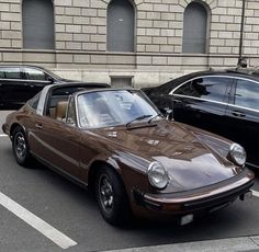 a brown car parked next to another black car in a parking lot with other cars