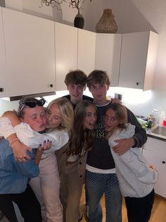 a group of young people standing together in a kitchen