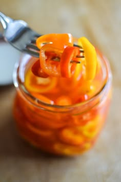 a jar filled with orange jello sitting on top of a wooden table next to a spoon