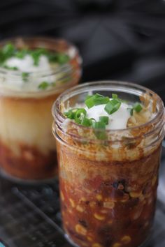 two jars filled with food sitting on top of a grill