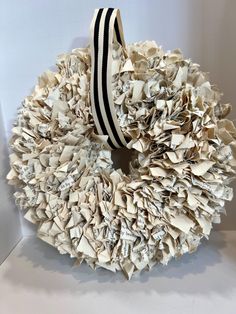 a wreath made out of old newspapers with a black and white ribbon on it's side