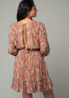 An ultra-flattering and versatile mini dress is a must for spring, summer and fall. This bohemian style is designed in a vintage-inspired orange paisley print, featuring voluminous long sleeves, a flirty surplice v-neckline, and a ruffle-trimmed tiered skirt. The open back with tie closure adds a breezy and playful touch. Paisley print Relaxed fit Long volume sleeve Elastic wrist cuff Mini length Ruffle-trimmed tiered skirt Surplice v-neckline Smocked elastic waist Back keyhole with tassel tie c Orange Long Sleeve Boho Dress, Orange Long Sleeve Bohemian Dress, Fall Paisley Print V-neck Mini Dress, Fall V-neck Mini Dress With Paisley Print, Orange Long Sleeve Boho Dress With Print, Flowy Long Sleeve Dresses With Paisley Print, Boho Print Long Sleeve Mini Dress For Fall, Long Sleeve Mini Dress With Boho Print For Fall, Fall Boho Print Long Sleeve Mini Dress