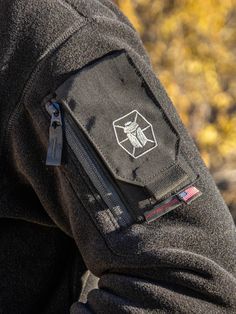 the back pocket of a man's black jacket with an insect patch on it