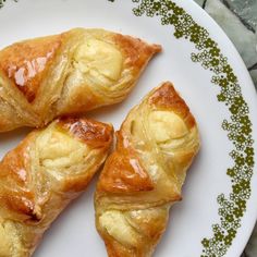 three croissants on a plate next to a cup of coffee