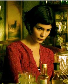 a woman sitting at a table with bottles and glasses