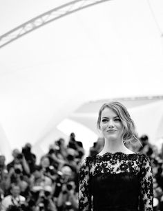 a woman standing in front of a crowd at a fashion show wearing a black and white dress